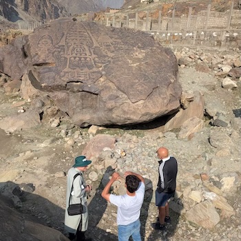 Researchers standing in next to a historical rock carving