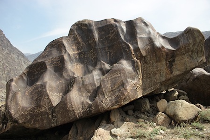 Large rock with many grooves and inscriptions on the side