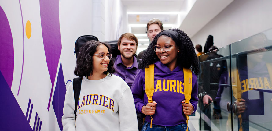 group of students walking in music hallway wearing Laurier hoodies