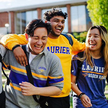 three students wearing Laurier gear and laughing