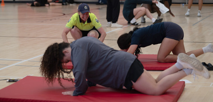 Young women doing push-ups beside a police officer at Brantford's Youth Engagement Series